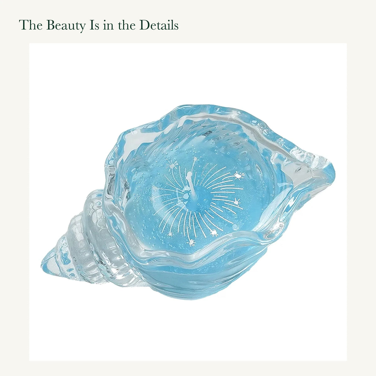Original blue conch-shaped glass candle with a white firework pattern and visible gel wax texture on white.
