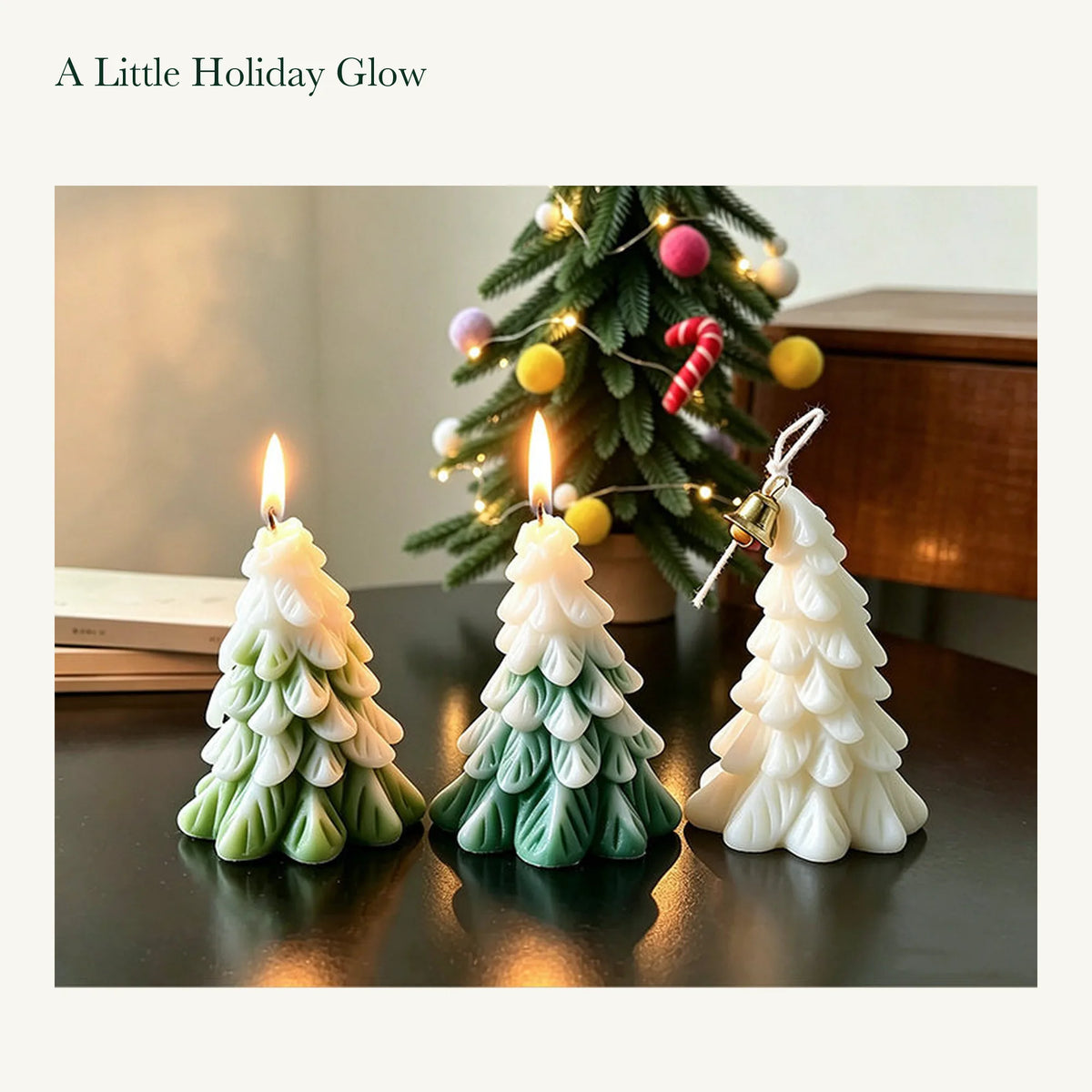 Green, olive green, and white tree candles on a wooden table beside a decorated Christmas tree.