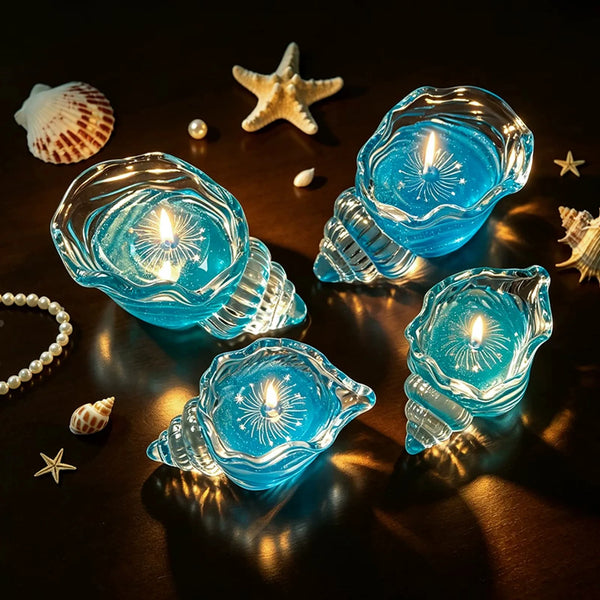 Blue and aqua conch-shaped glass candles glowing on a dark wooden tabletop with coastal styling props.