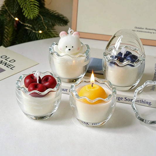 Bear, egg-yolk, cherry, and blueberry candle designs in original egg-shaped glass vessels in a home display.