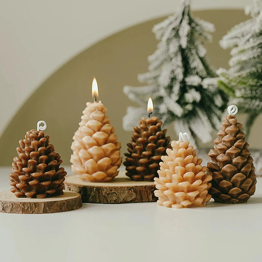 Original brown and light tan pinecone candles in tall and short shapes on wood slices with snowy evergreen decorations.