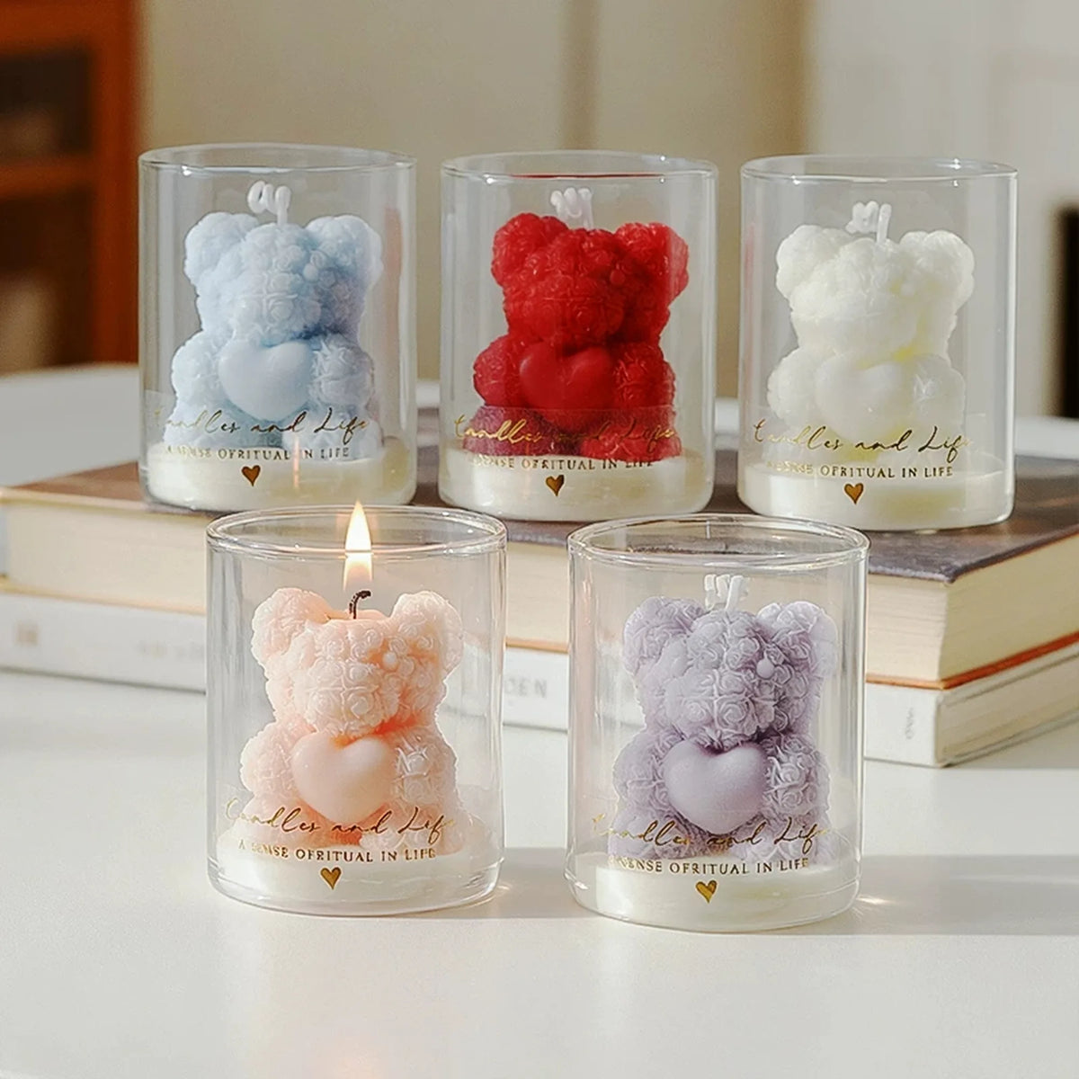 Five original rose-textured bear candles holding hearts in gold-printed glasses, displayed with books.