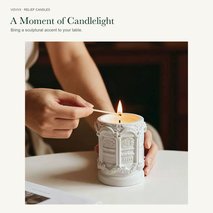 A hand using a match to light the original white Palace Relief candle on a table.