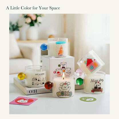 Five original illustrated glass candle styles arranged with their printed box in a bright home setting.