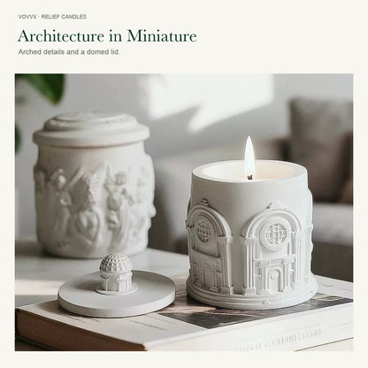Original white Roman Architecture candle lit beside its domed lid, with an Angel Relief candle in the background.
